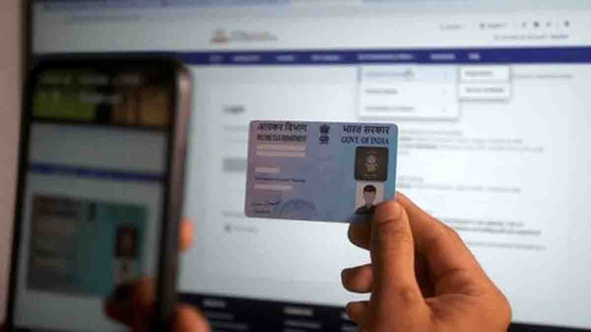 A woman in India updating her PAN card photo change online using a laptop at home with ID documents on the table