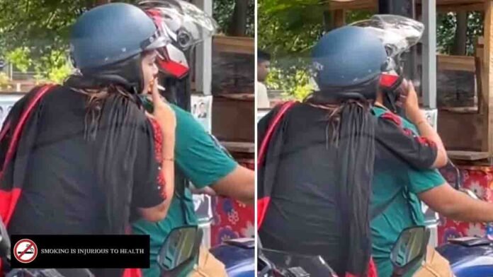 Indian woman sitting on a motorbike behind her husband, smoking a cigarette and handing it to him at a traffic signal, viral video moment