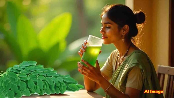 Glass of fresh moringa (drumstick leaves) water with raw leaves in the background