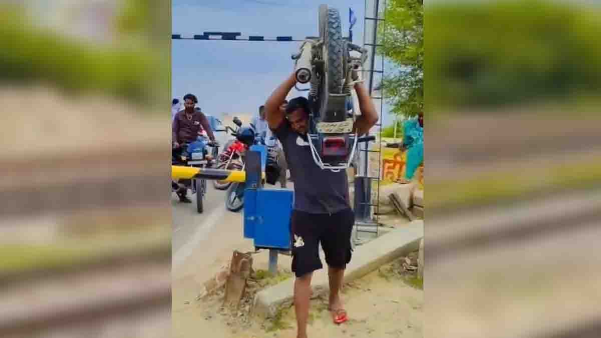 Man carries heavy bike on his shoulder at railway gate in Telangana viral video