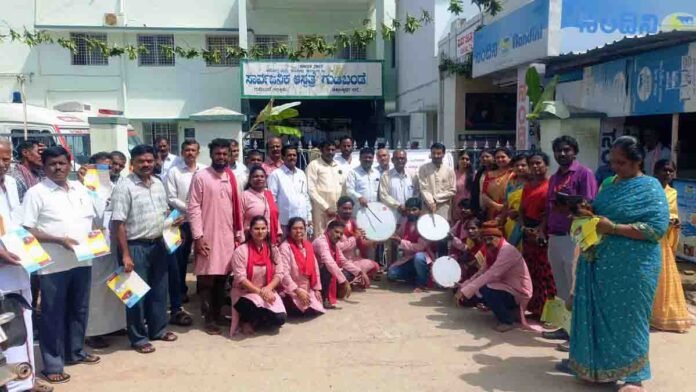 Street play promoting HIV awareness in Gudibande village, Chikkaballapur district, with villagers and healthcare workers observing the performance