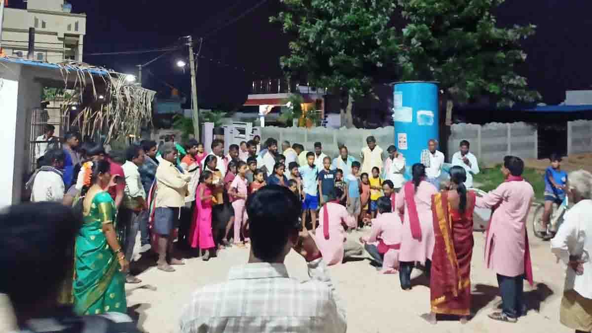 Street play promoting HIV awareness in Gudibande village, Chikkaballapur district, with villagers and healthcare workers observing the performance
