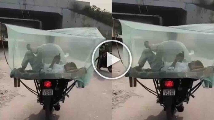Man lying on a cot tied to the back of a motorcycle with a mosquito net — viral Indian jugaad bedroom setup - Viral Video