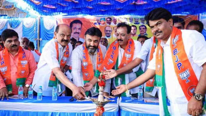MP Sudhakar distributing free helmets to two-wheeler riders during a road safety awareness program in Gudibande, Chikkaballapur district