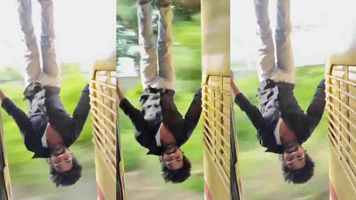 Train Stunt Viral Video showing a young man hanging upside down from the door of a moving train while performing a dangerous stunt for social media.