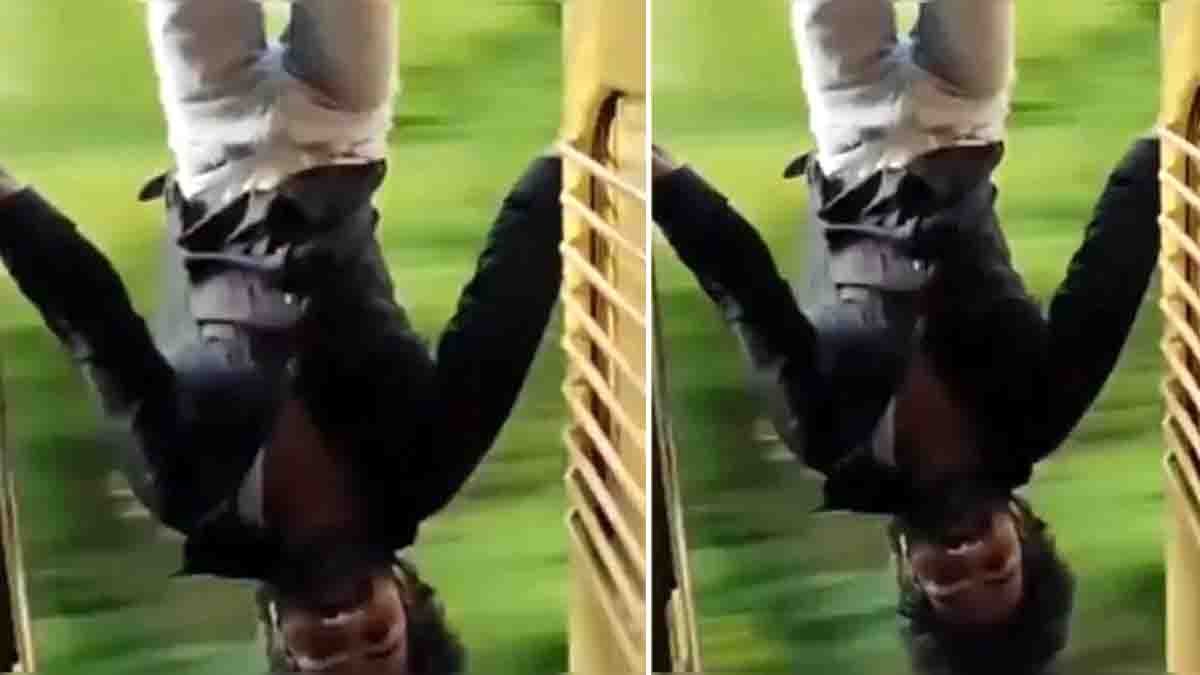 Train Stunt Viral Video showing a young man hanging upside down from the door of a moving train while performing a dangerous stunt for social media.
